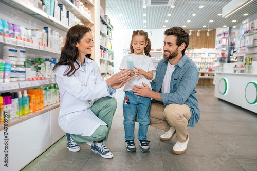 Fotografie Smiling woman in lab coat advising man and child indoors in modern drugstore