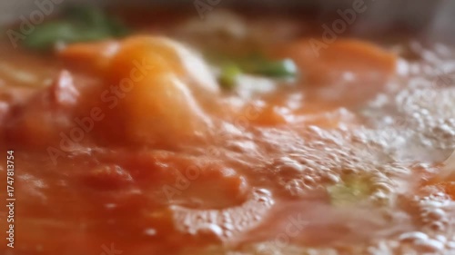 Vegetables simmer in bubbling water as they cook in a pot.