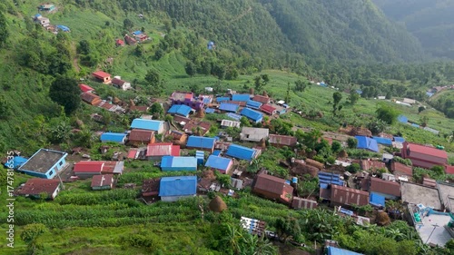 High Angle Aerial View of a Traditional Hillside Village in Nepal. Himalayan Settlement with Colorful Roofs on Green Terraced Slopes.
