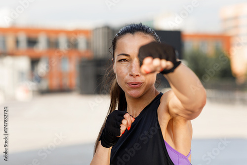 Canvas Print Young female practicing punches outdoors, wearing gloves