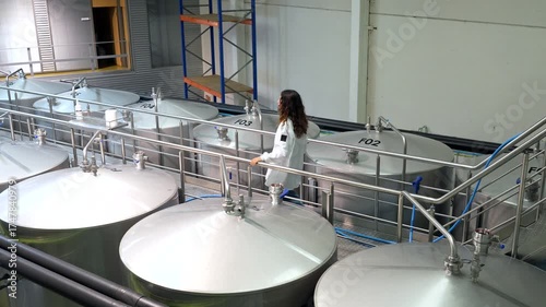 Female brewery worker inspecting fermentation tanks
