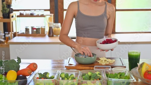 Fitness woman woman preparing a healthy yogurt bowl topped with fruits and nuts