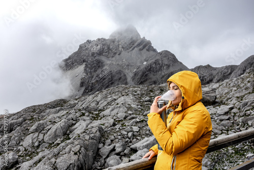 Woman recovering from altitude sickness using canned oxygen during cold mountain travel