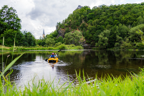 Woman Paddling a Packraft on the Saxon Saale with Reed in the Foreground and Hirschberg Church in the Background