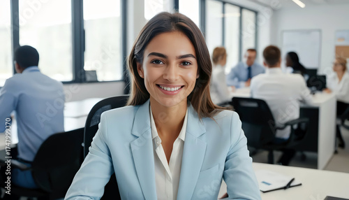 Smiling Businesswoman in Office Setting with Colleagues in Background.