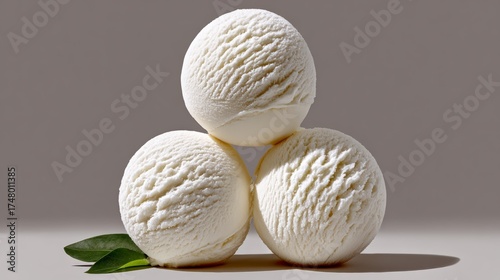 Three ice cream balls stacked on top of each other. The ice cream is white and the leaves are green