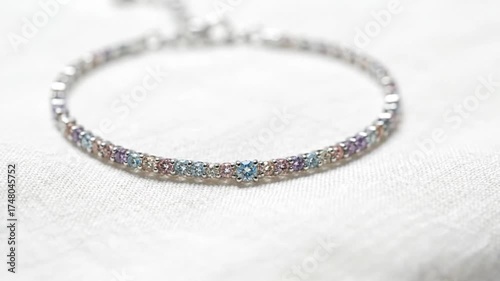 Delicate silver bracelet adorned with pastel gemstones on a soft fabric backdrop
