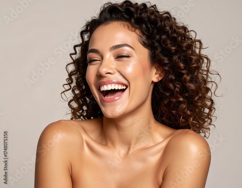 A joyful woman with curly hair, radiant skin, and a happy expression