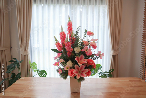 Elegant flower arrangement in a vase placed on a wooden table with soft sunlight and curtain background. Modern minimalist interior design concept showing natural beauty, cozy lifestyle, and home deco
