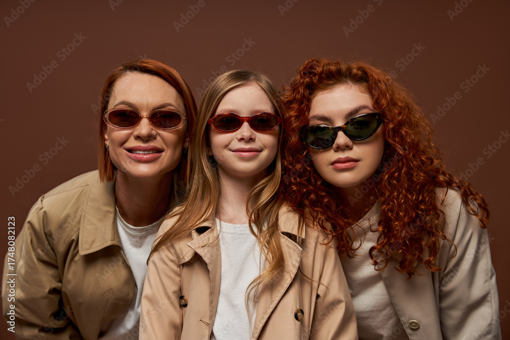 Obraz premium Three generations share smiles in stylish autumn attire with vibrant red hair