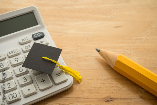 Graduation cap, white calculator and pencil on table. Tuition, expense calculating for education, repayment student loan or debt, savings for education, scholarship for studying abroad concept.