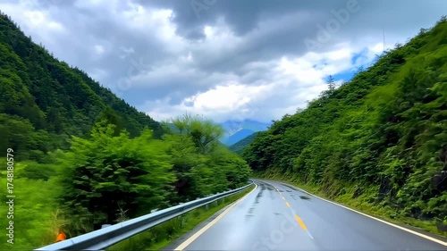 Winding mountain road through lush green forests under a cloudy sky