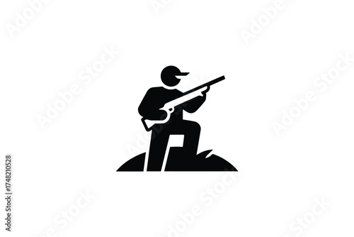 Silhouette of a hunter aiming a rifle in a field at dawn