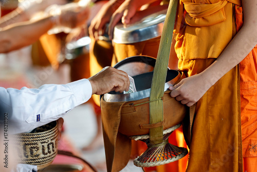Buddhist monks in orange robes at  morning alms giving ceremony. Worshipers give alms and food. Luang Prabang.  Luang Prabang. Laos.