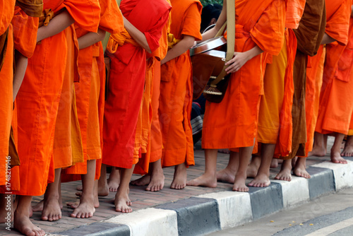 Tableau sur toile Barefooted Monks walking in procession wearing saffron robes during morning alms giving in Luang Prabang