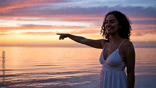 Woman pointing toward the ocean during sunset