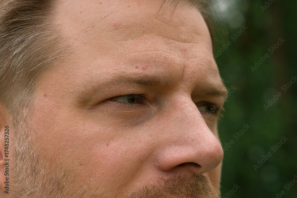 Fototapeta premium Human Man Face extreme close up. Macro Shot of Male Green Eye. Vision. Healthy Eyesight Concept. Front view. Mature Adult Looking at Camera, Blinking Eyelashes. Eye Opening Wide. Soft Selective Focus