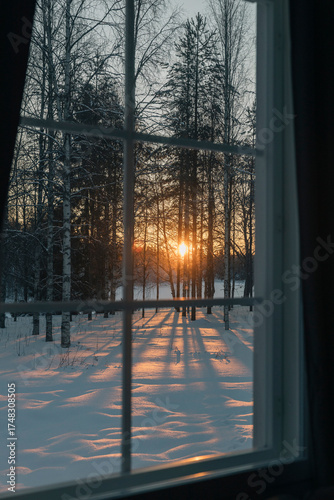 Winter sunset shining through window on snowy landscape