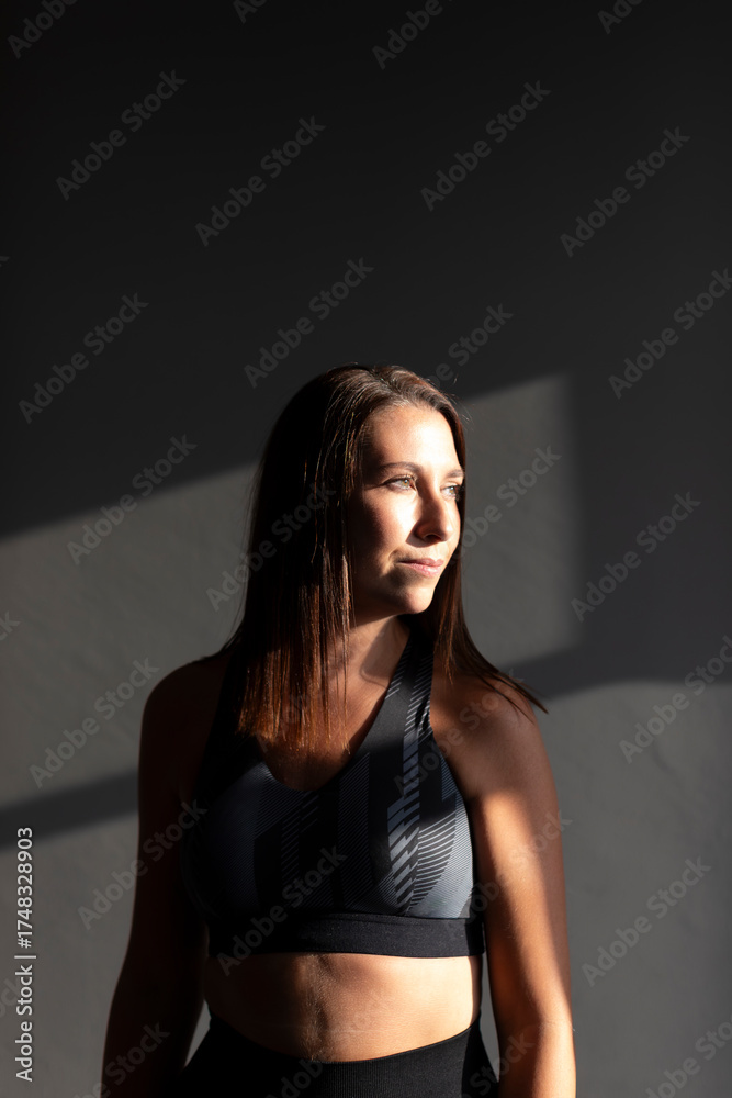 Naklejka premium Portrait of a young woman, deep in thought, dressed in sportswear, during a Pilates class in a small gym