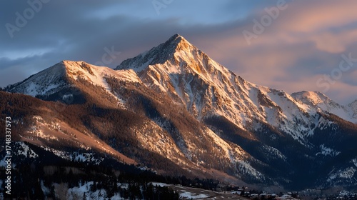 Golden Sunlight on Snow-Covered Mountain Peak. Majestic Alpine Landscape Bathed in Warm Light at Dawn or Dusk.