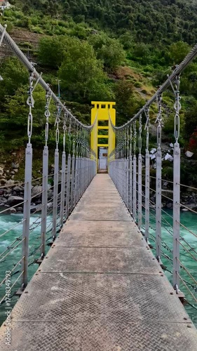A panoramic view and close-up perspective of a vibrant yellow suspension bridge crossing the turquoise Swat River, framed by the lush, towering mountains of Khyber Pakhtunkhwa, Pakistan.