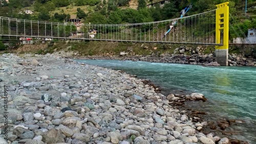 A panoramic view and close-up perspective of a vibrant yellow suspension bridge crossing the turquoise Swat River, framed by the lush, towering mountains of Khyber Pakhtunkhwa, Pakistan.