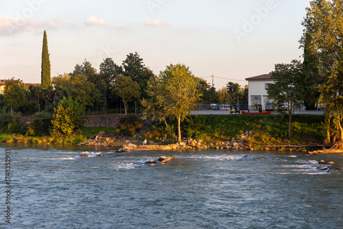 A scenic landscape capturing a moment of leisure and relaxation. A fisherman sits on the rocks while others chat, embodying a tranquil, slow-paced lifestyle.