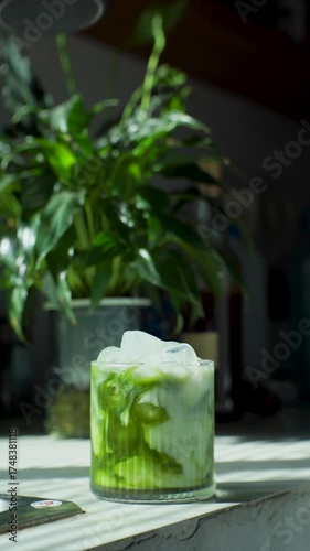 Pour milk into glass with ice and tea to make cold matcha green tea with fresh milk at home.