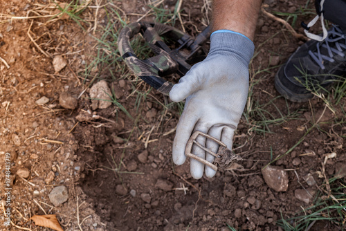 A man's hand with a metal detector holds a found buckle.