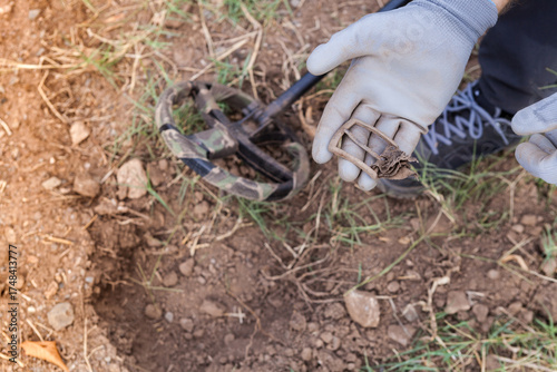 A man's hand with a metal detector holds a found buckle.