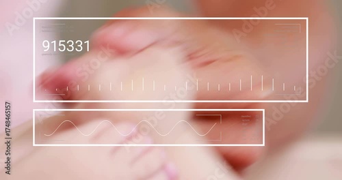 Adult hand flexing baby foot while HUD overlay fades in, updating numeric bars monitoring movement