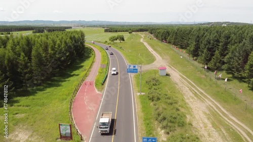 Aerial shot lone car driving on a winding asphalt road through lush green forest