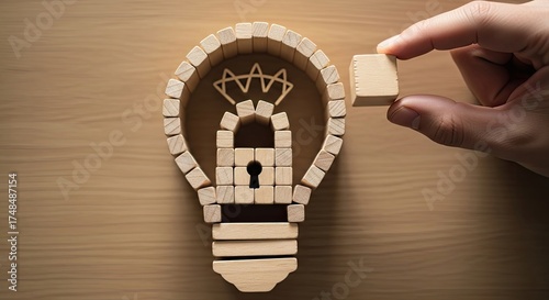 Hand Placing Wooden Block Completing Light Bulb with Lock on Wooden Tabletop