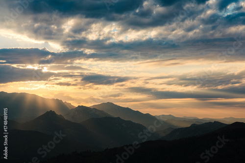 Golden hour sunlight and crepuscular rays break through dramatic clouds over the Cantabrian mountains in Asturias, Spain.