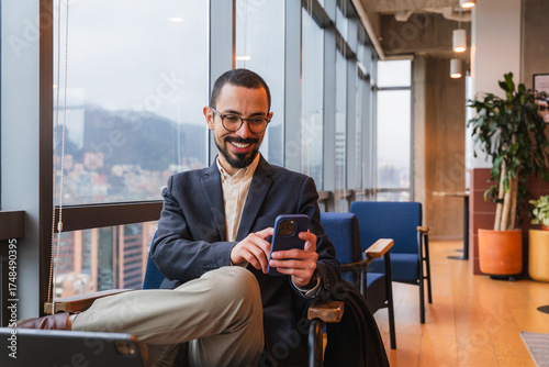 Young professional man networking, working, and texting in a modern co working space