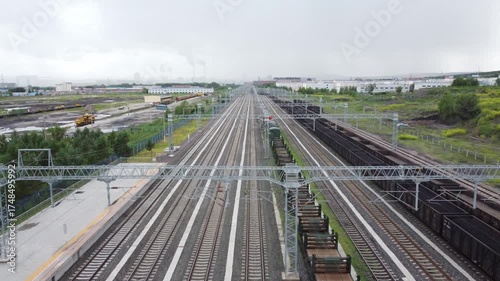 Modern electric passenger train moving along multiple tracks at a large freight depot