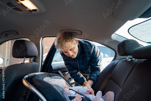 Father putting baby in safety car seat happy family vacation road trip lifestyle child care transportation rear-facing. Caring parent secures baby by fastening with seat belt. Selective focus.