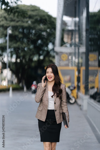 фотографія Woman on the phone : A portrait of an elegant woman walking on the street confidently while talking on her phone, exuding poise and self-assurance