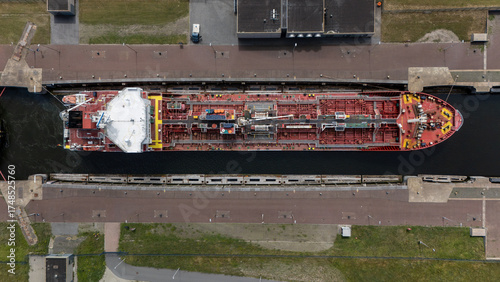 Photos Drone aerial view of a large cargo ship passing through a lock in IJmuiden Harbor, Netherlands, showing maritime infrastructure and logistics