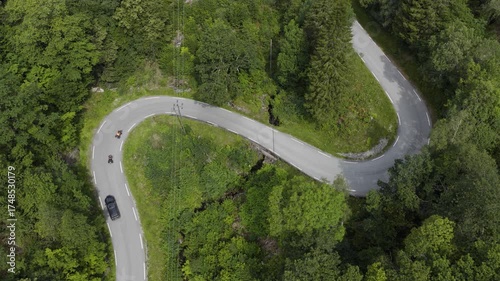Sharp hairpin road curve surrounded by dense forest aerial view