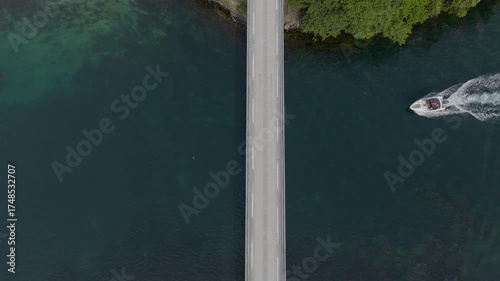 Aerial view of bridge with car and boat crossing clear blue water