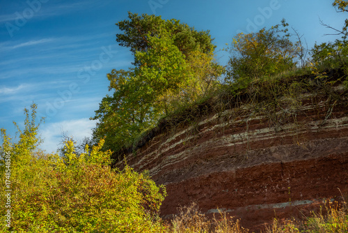 Vibrant stratified earth bank contrasts with a bright blue sky.