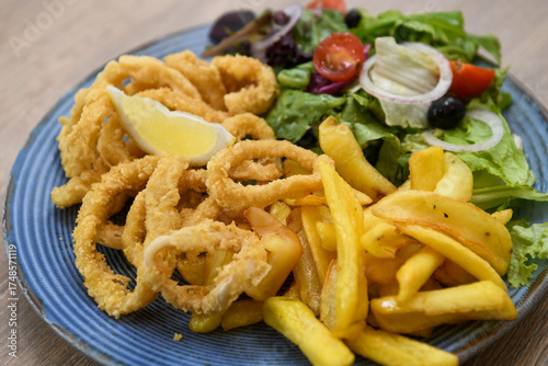 Fotografie Fried squid rings with french fries and salad