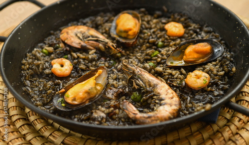 Fototapeta Naklejka Na Ścianę i Meble -  Paella with black rice, mussels and shrimps in a pan
