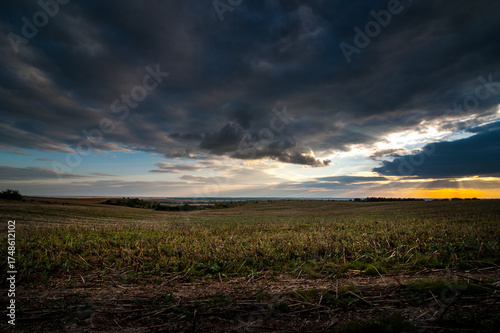 dramatic dark storm sky with clouds at sunset over the field with stubble aft...