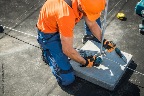 Bild auf Leinwand Construction Worker Installing Lightning Protection Rod on Rooftop During Daytim