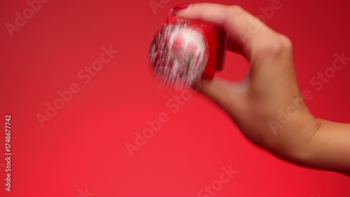 A Christmas snow globe is being shaken and held in a hand. A woman's hand shaking a Christmas snow globe. Christmas decorations. Xmas