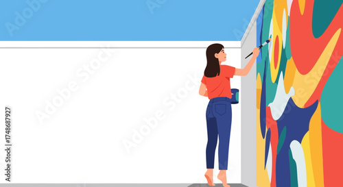 Woman artist is painting a colorful mural on a wall with a brush and a palette