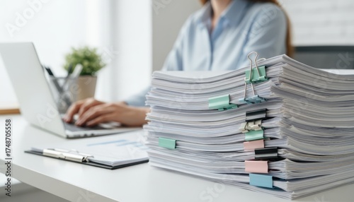 Business woman working on laptop computer with stack of paper document for searching and checking document on folder paper at busy work on desk office, close up