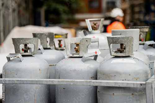 Photography Multiple silver propane gas bottles arranged in metal holder outdoors on constru